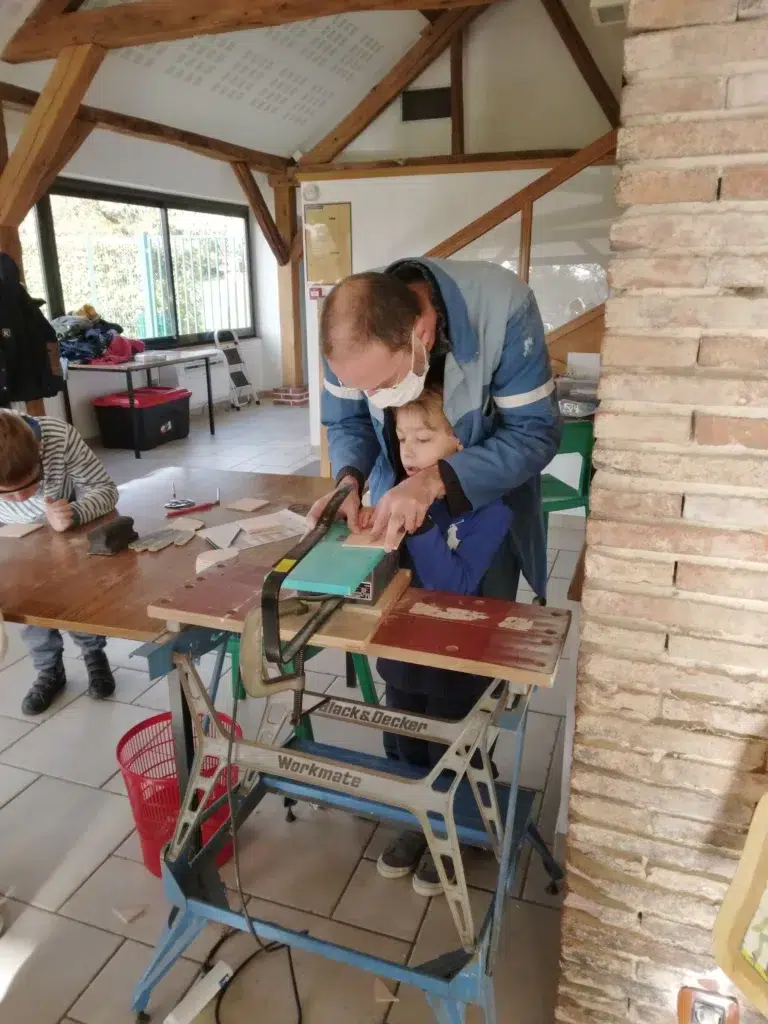 Animateur menant un atelier bois pour créer une boule de noel